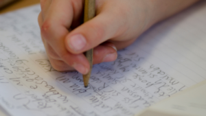 Hand holding a pencil and writing on a paper